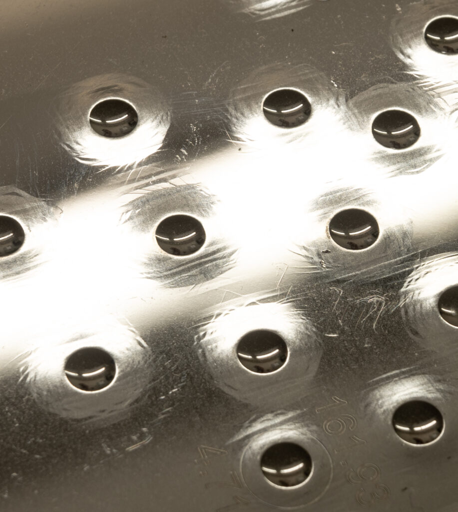 The surface of a Brinell test block showing the distortions caused by indentations, ie the raised level of the steel surface around each indentation